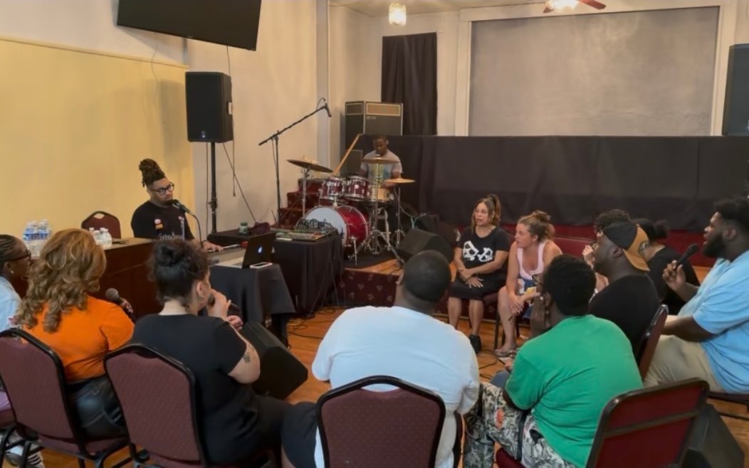 The Shift choir rehearsing in a circle with keys and drums