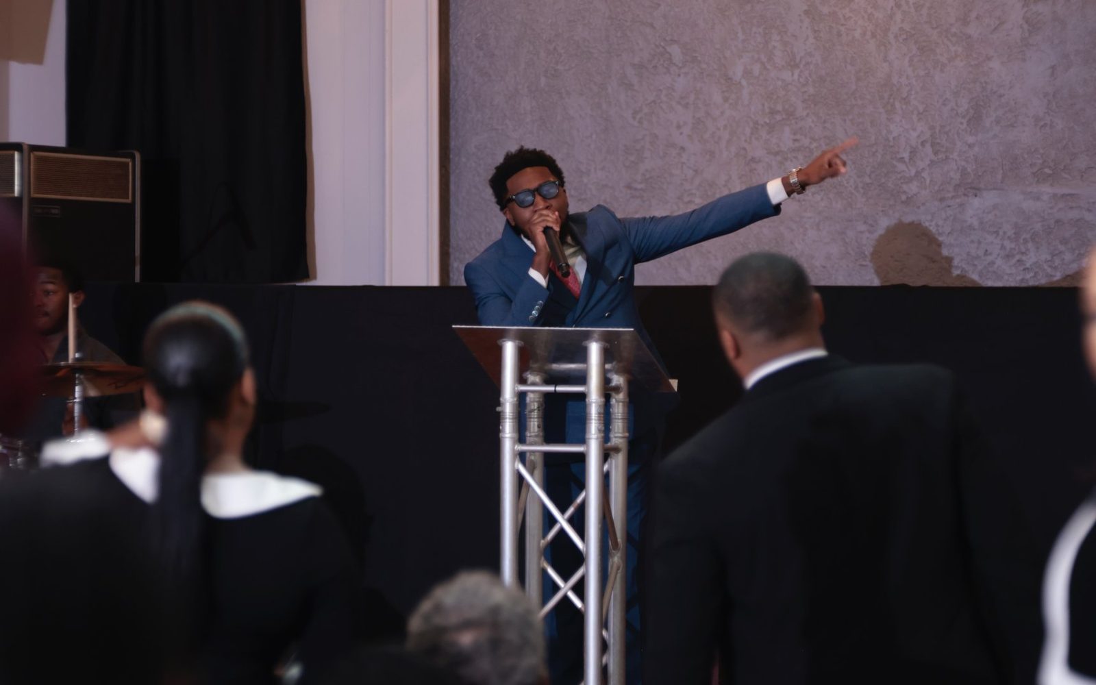 Pastor Jahleel Spence preaching at the pulpit, pointing toward the congregation